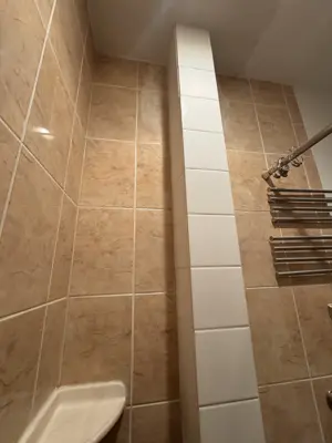 finished bathroom tile repair featuring white accent tile column flush with beige wall tiles in nyc