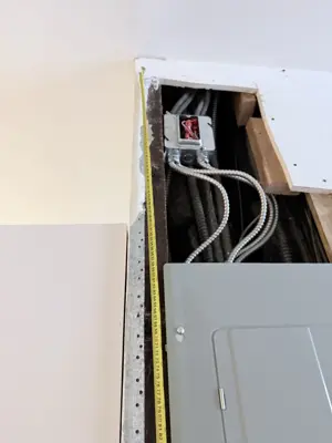 Electrical wiring and junction box exposed in ceiling during panel installation work in NYC