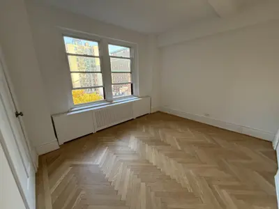 Freshly installed herringbone hardwood parquet flooring in a bright NYC apartment bedroom