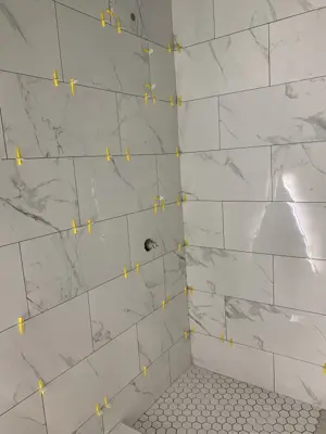 marble-look porcelain shower wall tiles with leveling clips and hex mosaic floor nyc