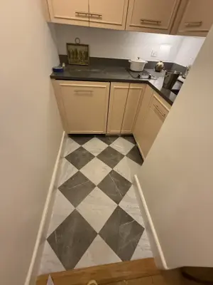 completed checkered tile floor installation in a nyc kitchen or utility area with white cabinetry
