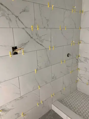 marble-look porcelain tile installation in progress in nyc bathroom shower with tile spacers