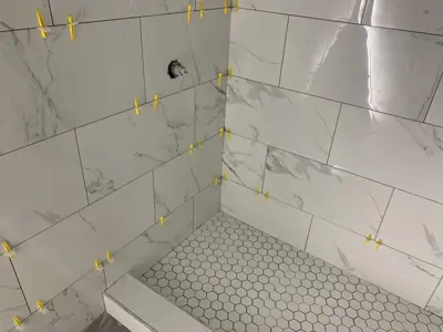 marble-look wall tiles with leveling clips during shower installation in nyc bathroom