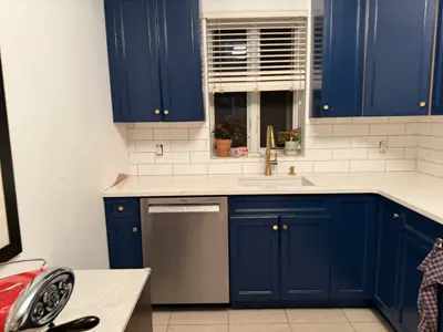 completed nyc kitchen renovation featuring blue cabinets, white subway tile backsplash, quartz countertops, and stainless dishwasher