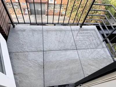 completed outdoor balcony tile installation with large format gray stone tiles in nyc