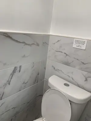 clean bathroom with marble-look tile walls and modern toilet installation in nyc