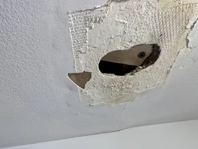 Large hole in ceiling drywall with mesh tape and exposed damage before repair in NYC home