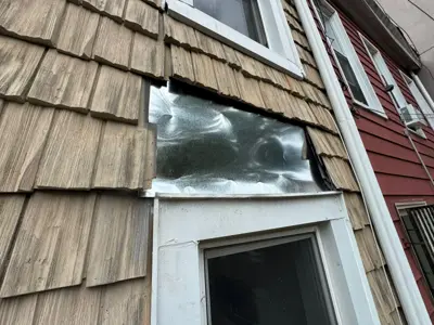 Repaired exterior wall with new flashing installed beneath wood shingles on NYC residential building