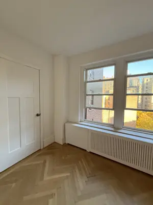 Freshly painted bright white room with herringbone hardwood floors in NYC apartment