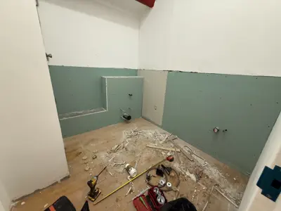 bathroom renovation in progress showing drywall installation with tools and debris on floor in nyc