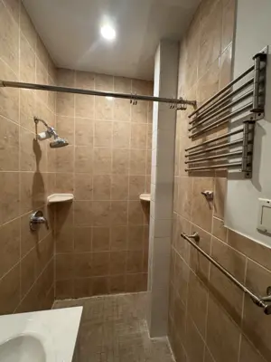 completed nyc bathroom renovation with tiled shower, curtain rod, and heated towel rack installation
