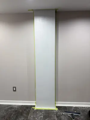 Drywall repair with painter's tape masking in NYC apartment room during skim coat process
