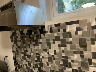 completed modern mosaic tile backsplash installation behind kitchen range hood in nyc home
