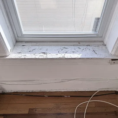 Window sill with paint flaking away in sheets before repair