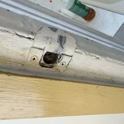 Sash pulley painted over in the window jamb, paint cracked around the plate