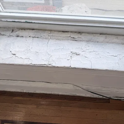 Close view of a cracked and crazed window sill before repair