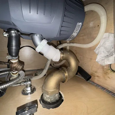 Garbage disposal mounted under a kitchen sink with discharge tube and dishwasher hose connected