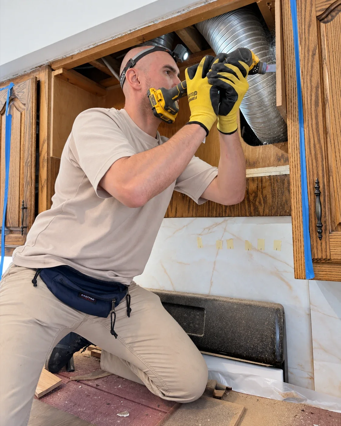 Repair ASAP owner cutting a vent opening in a kitchen cabinet